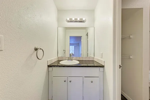 a bathroom with a granite countertop sink and a mirror