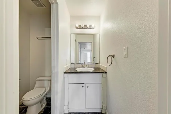 a bathroom with a granite countertop toilet sink and mirror