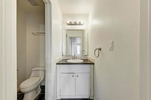 a bathroom with a granite countertop toilet sink and mirror