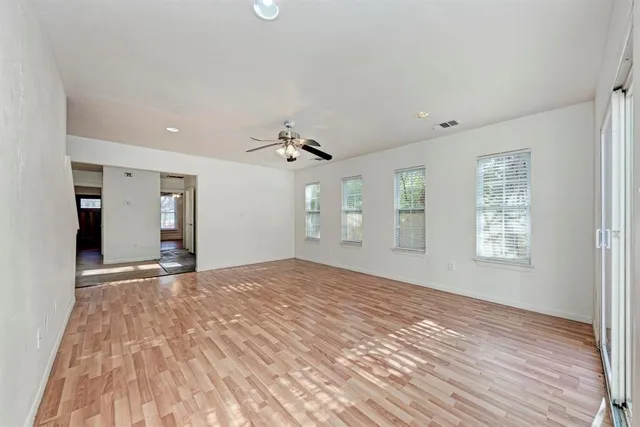 a view of an empty room with window and wooden floor