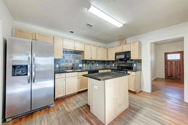 a kitchen with stainless steel appliances granite countertop a refrigerator a stove top oven a sink and dishwasher with wooden floor