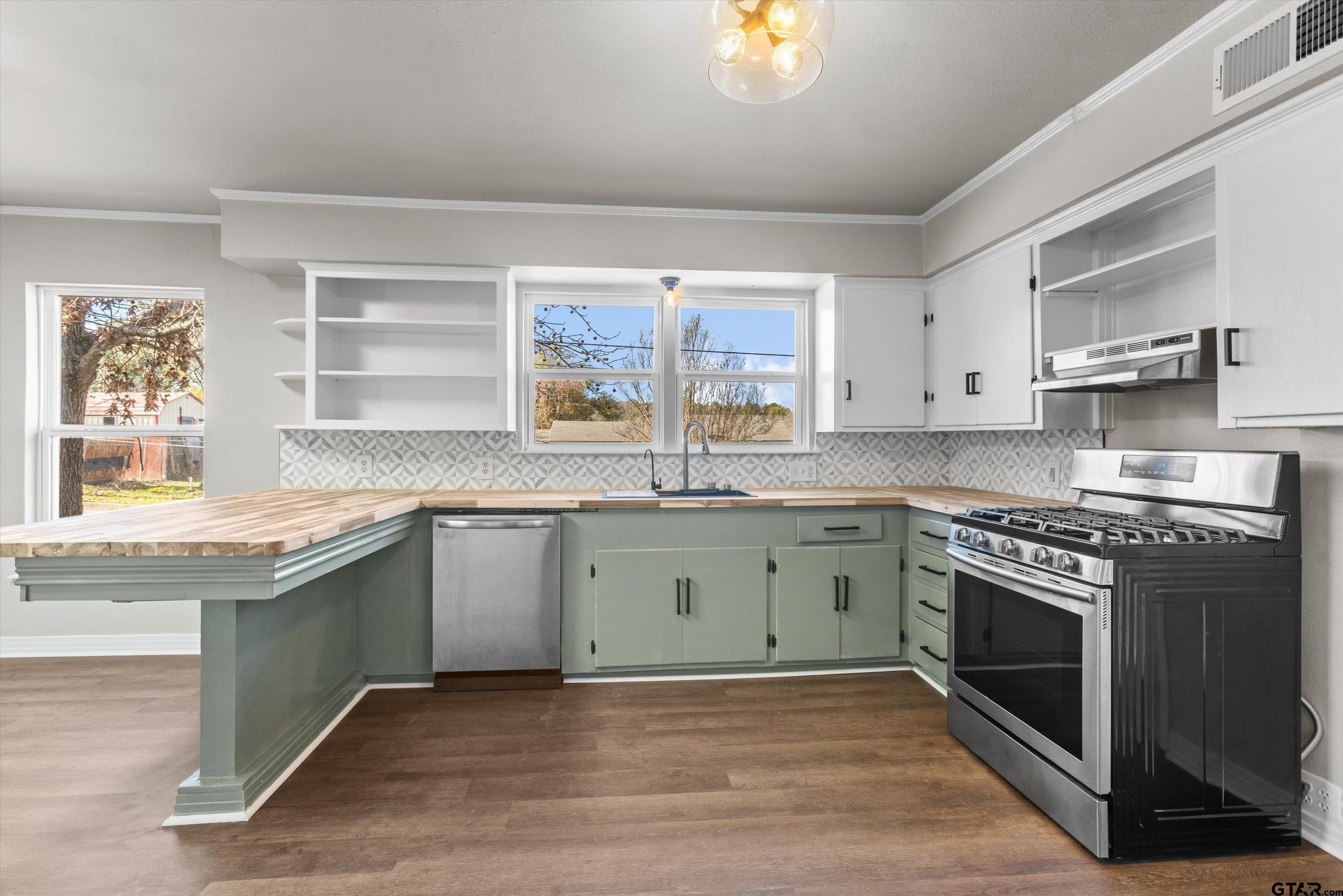 1330 Graham Drive Tyler, TX 75701 - Photo 6 of 22 a kitchen with granite countertop a stove a sink and dishwasher with wooden floor