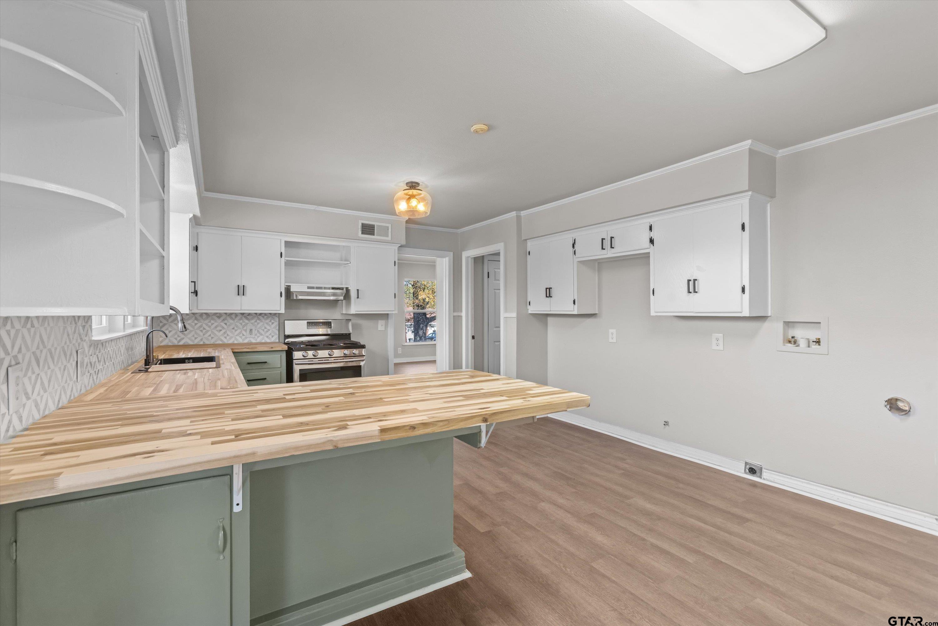 1330 Graham Drive Tyler, TX 75701 - Photo 7 of 22 a kitchen with a wooden floor and white cabinets