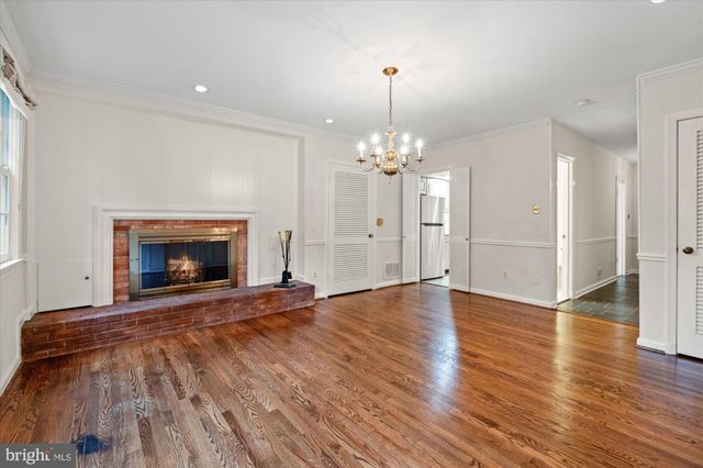 a view of an empty room with wooden floor fireplace and a window