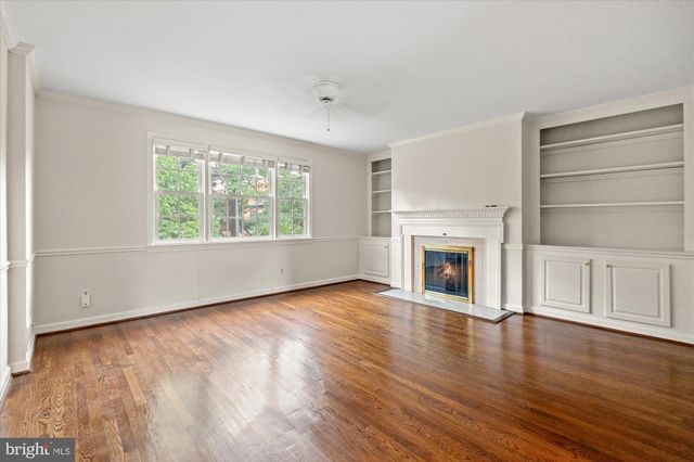 an empty room with wooden floor fireplace and windows