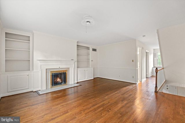 a view of an empty room with wooden floor fireplace and a window