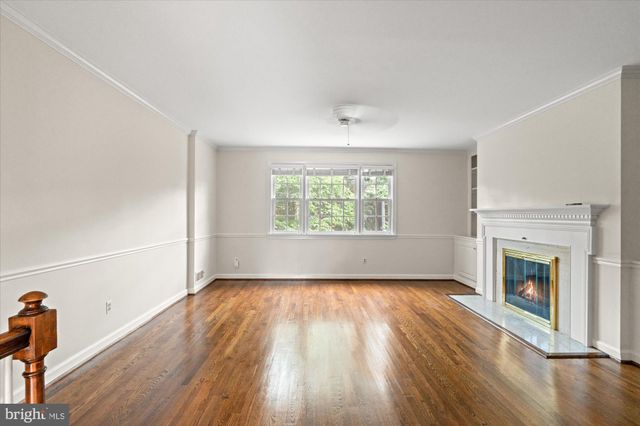 an empty room with windows a fireplace and wooden floor