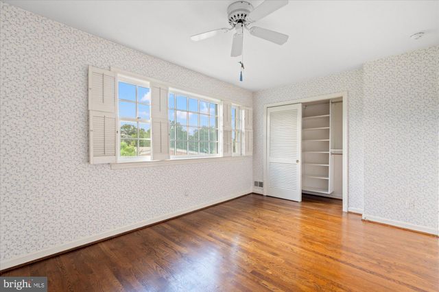an empty room with wooden floor chandelier fan and windows