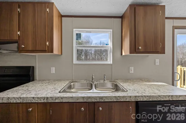 a kitchen with granite countertop a sink a stove and a wooden cabinets