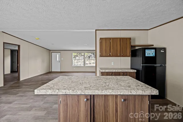 a kitchen with granite countertop a refrigerator and wooden cabinets