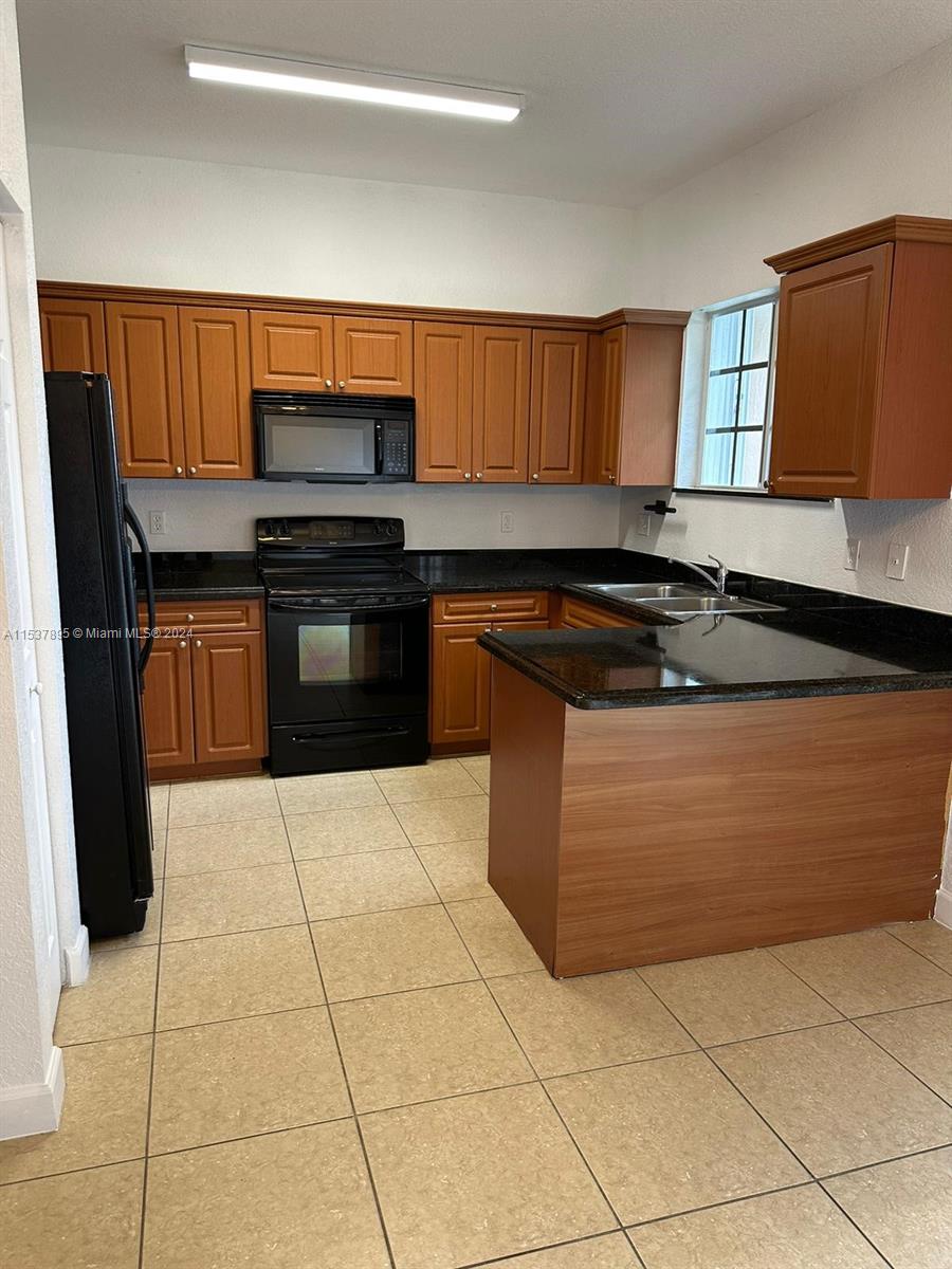 a kitchen with granite countertop a stove a sink a counter space and cabinets