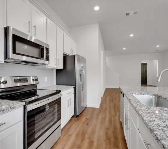 a kitchen with stainless steel appliances granite countertop a stove microwave and sink