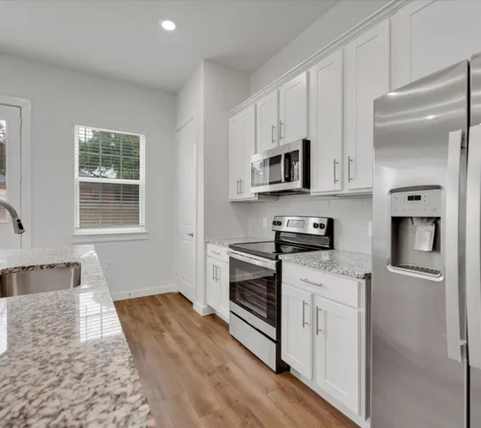 a kitchen with stainless steel appliances granite countertop a stove a sink and a refrigerator