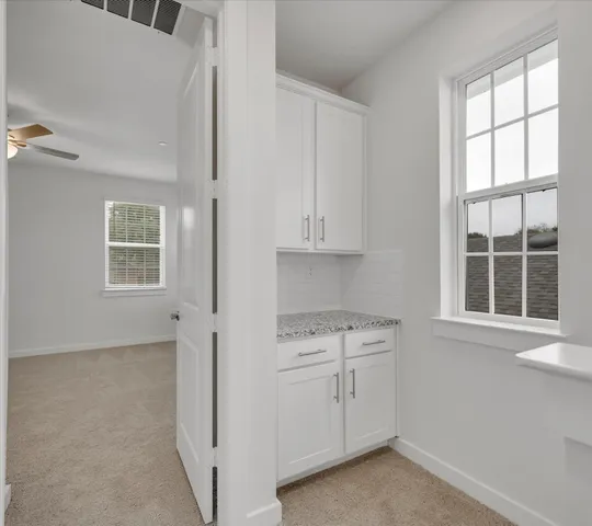 a view of a kitchen with white cabinets and window