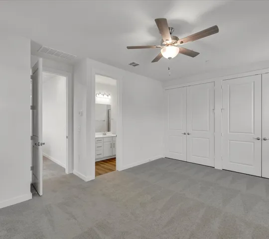 a view of an empty room with chandelier fan