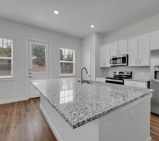 a kitchen with granite countertop a sink a counter top space appliances and cabinets
