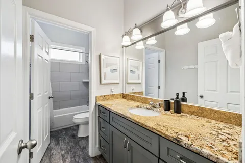 a bathroom with a granite countertop sink a toilet and shower