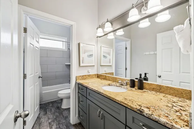 a bathroom with a granite countertop sink a toilet and shower