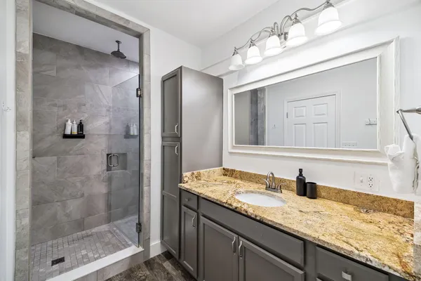 a bathroom with a granite countertop sink mirror and shower