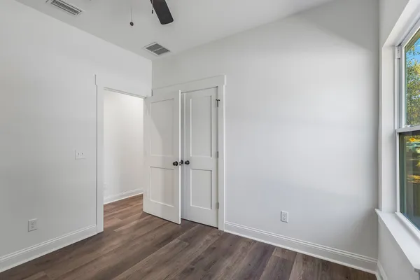 an empty room with wooden floor and windows