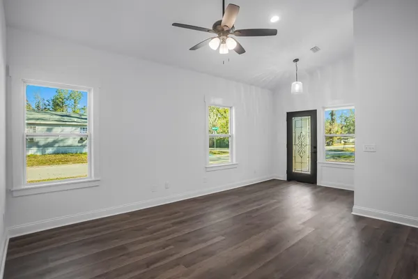 a view of an empty room with a window and wooden floor
