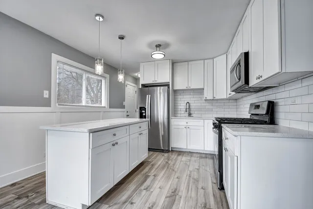 a kitchen with a sink a center island cabinets and stainless steel appliances