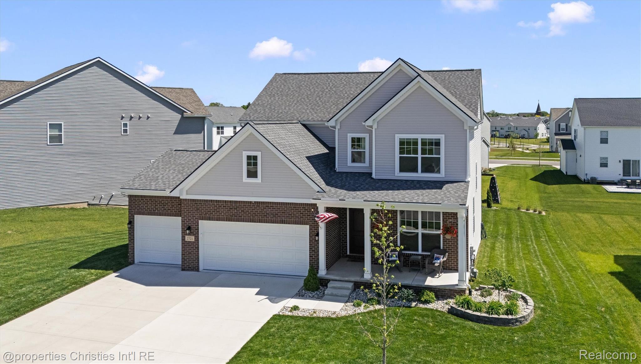 2721 Maize Loop Saline, MI 48176 - Photo 2 of 52 View of front of home featuring a porch, a front lawn, concrete driveway, roof with shingles, and brick siding