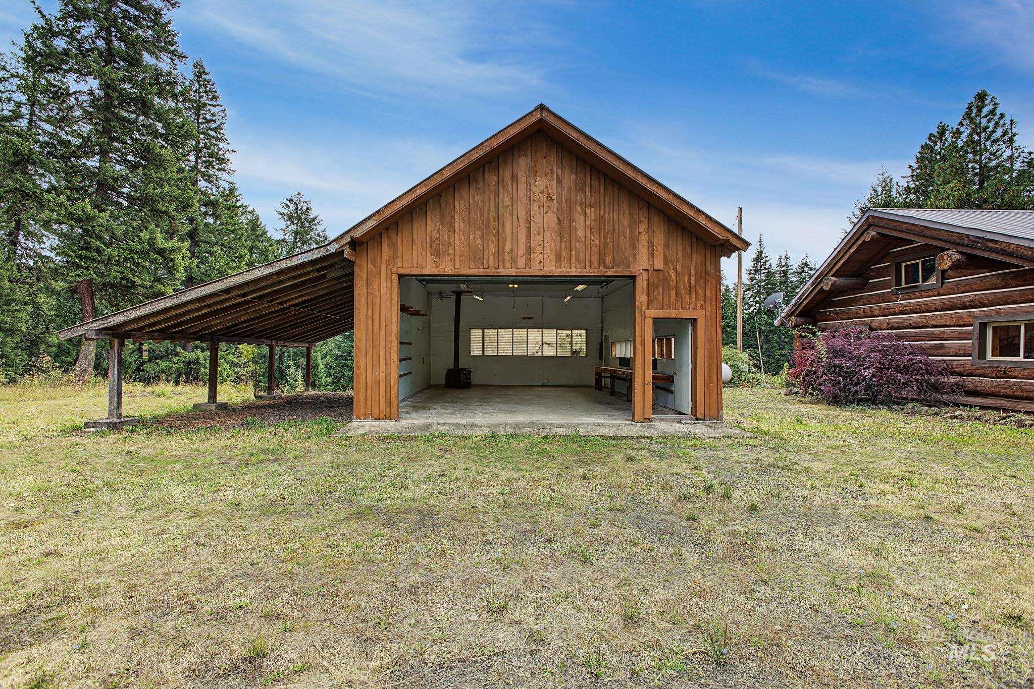 Wood-sided outbuilding with an attached lean-to and a large roll-up garage door
