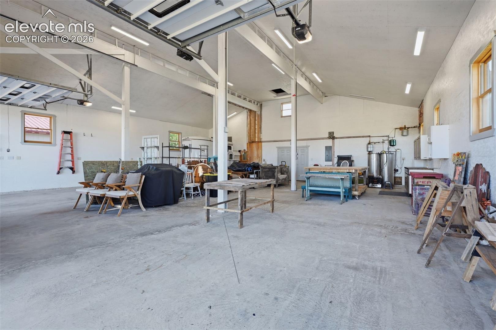 6015 West Condor Road Peyton, CO 80831 - Photo 48 of 50 Expansive concrete flooring with exposed beam ceilings, multiple windows, and fluorescent overhead lighting