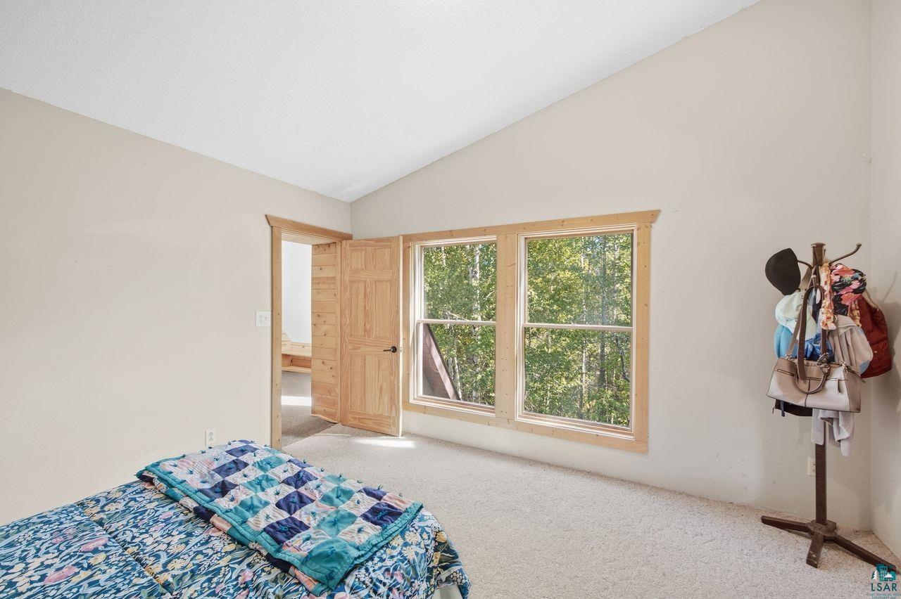 65889 Old County Road Marengo, WI 54855 - Photo 12 of 44 Vaulted ceiling, natural wood trim, double windows, wood panel doors, and neutral carpeting