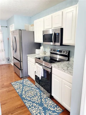 a kitchen with stainless steel appliances kitchen island granite countertop a refrigerator stove and microwave