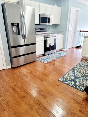 a kitchen with stainless steel appliances a stove a microwave and wood floor