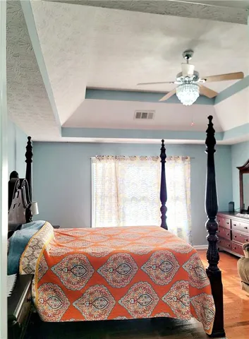 a bedroom with a bed and dresser with chandelier