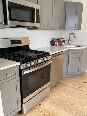 a kitchen with granite countertop cabinets stainless steel appliances and wooden floor