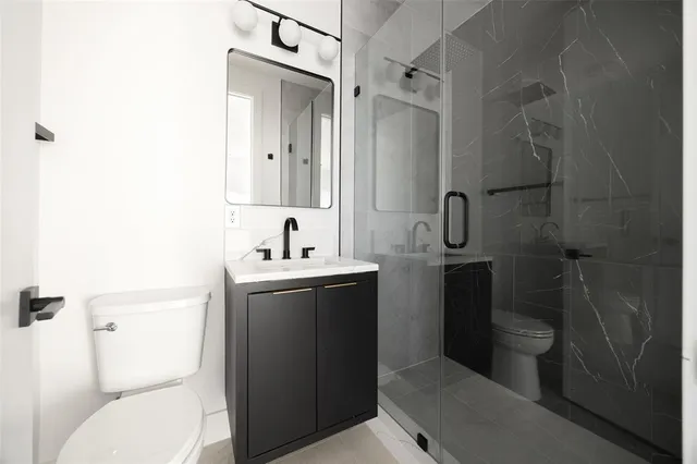 a bathroom with a toilet sink vanity and mirror
