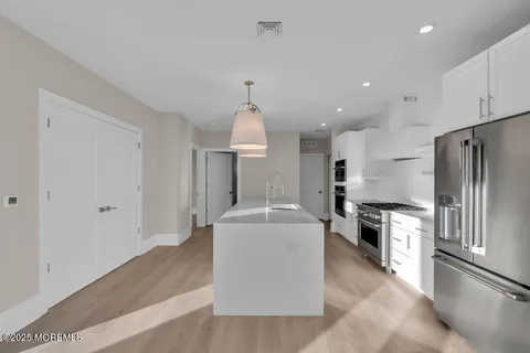 a kitchen with kitchen island a stove a refrigerator and a sink