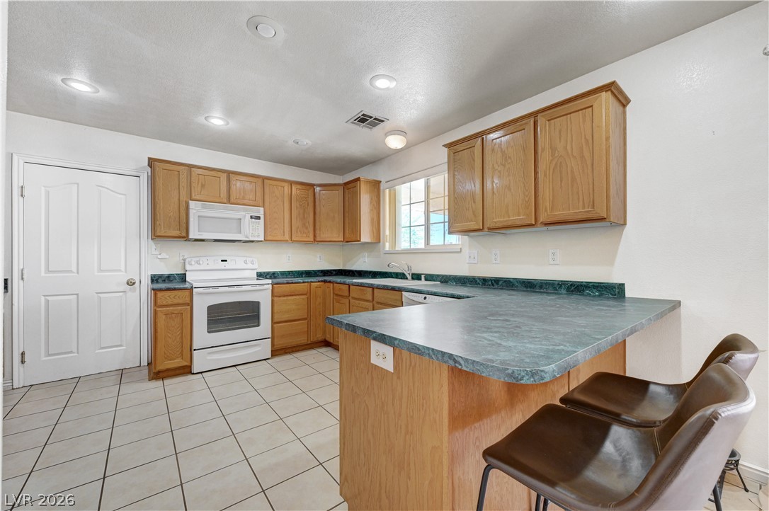 1272 Liston Avenue Logandale, NV 89021 - Photo 18 of 61 A well-lit kitchen with natural wood cabinetry and a functional breakfast bar.