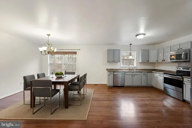 a kitchen with stainless steel appliances granite countertop a stove a sink a microwave a dining table and chairs