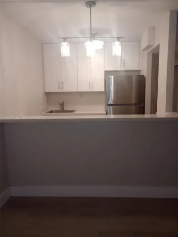 a view of a kitchen with a sink wooden cabinets and a window