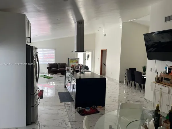 a living room with furniture a flat screen tv and kitchen view