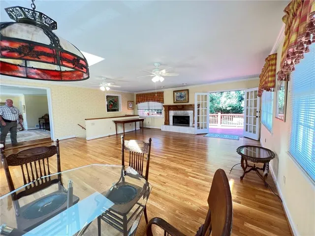 a view of a dining room with furniture one side kitchen view and wooden floor