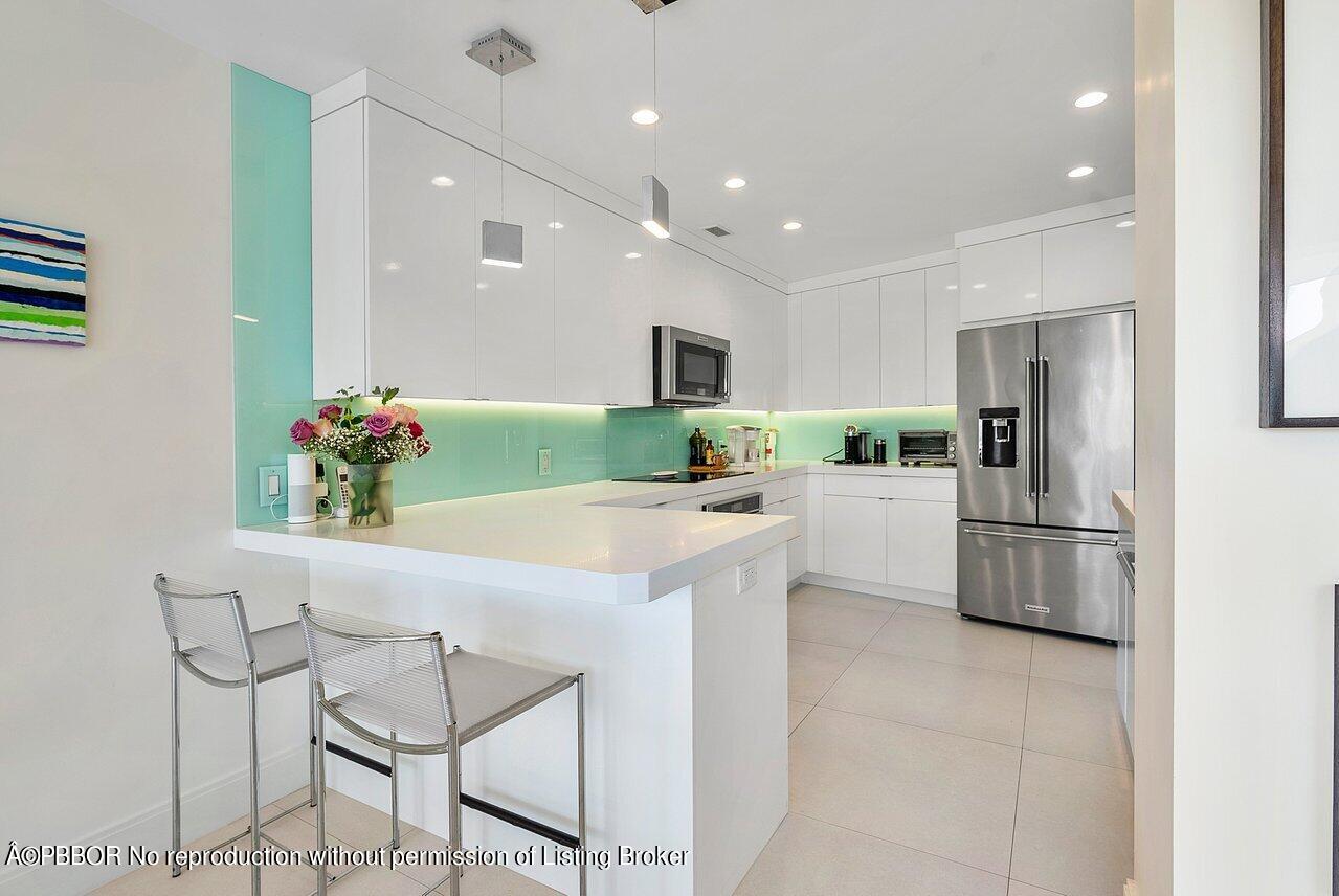 44 Cocoanut Row, Unit 122B Palm Beach, FL 33480 - Photo 6 of 21 a kitchen with kitchen island white cabinets and stainless steel appliances