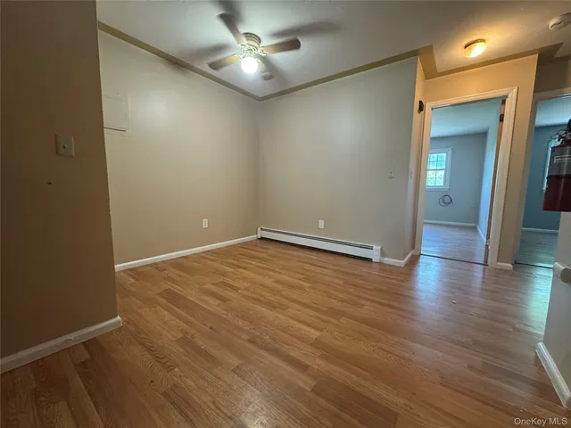 an empty room with wooden floor and a ceiling fan