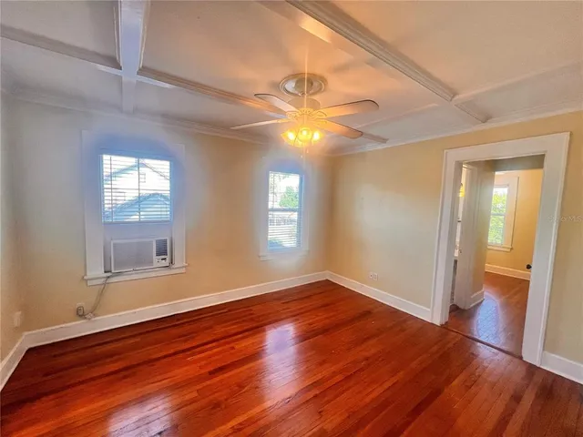 a view of empty room with wooden floor and fan
