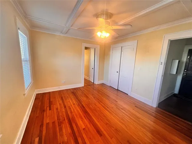 a view of empty room with wooden floor and fan