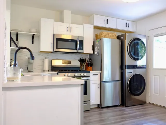 a kitchen with stainless steel appliances granite countertop a stove a sink dishwasher and a refrigerator with wooden floor