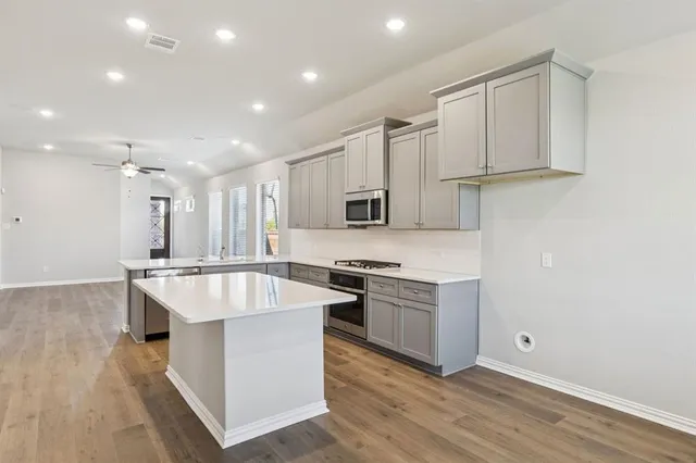 a large white kitchen with stainless steel appliances granite countertop a stove and a sink