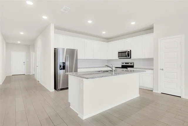 a kitchen with stainless steel appliances a refrigerator sink and white cabinets