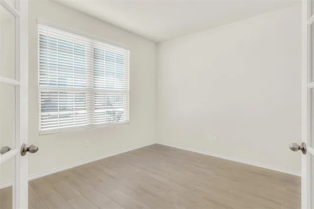 a view of an empty room with wooden floor and a window