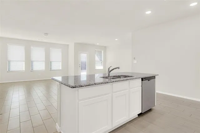 a kitchen with granite countertop a sink and white cabinets
